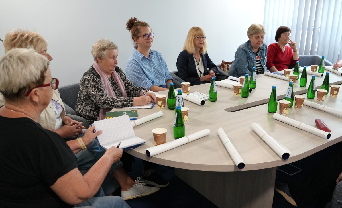 Seniorzy siedza przy stole i rozmawiają