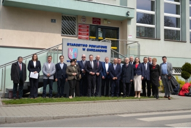 Kobiety i mężczyźni pozują do zdjęcia przed budynkiem starostwa