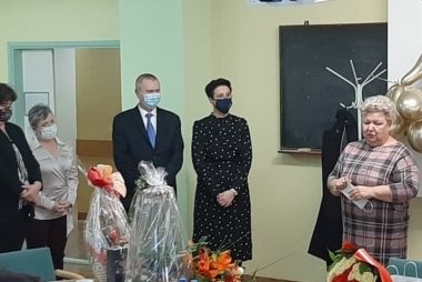 na zdjęciu 4 osoby 3  kobiety i mężczyzna  składajace życzenia Pani alicji Dobranowskiej, zdjęcie w biurze w tle złote balony, na 1 planie zestawy prezentowe 