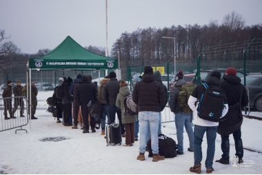Zdjęcie kilkunastu osób stojących w kolejce do namiotu na zewnątrz. 