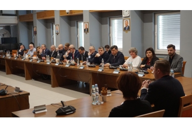 Zdjęcie kilkunastu osób zasiadających przy stołach z jednej strony sali narad w starostwie powiatowym w Chrzanowie. W prawym dolnym rogu zdjęcia widać Starostę i Wicestarostę.