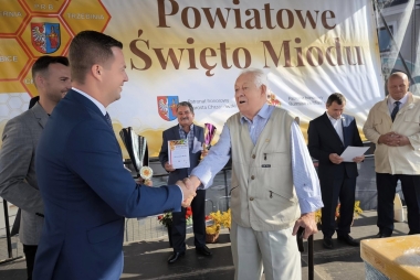 Mężczyzna w garniturze podaję rękę starszemu mężczyźnie 