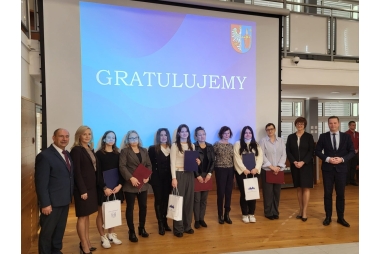 Zdjęcie władz powiatu, uczennic, rodziców, nauczycieli i dyrekcji szkół. Na zdjęciu znajduje się 12 osób. W tyle, na rzutniku wyświetlony jest napis GRATULUJEMY oraz herb powiatu Chrzanowskiego.