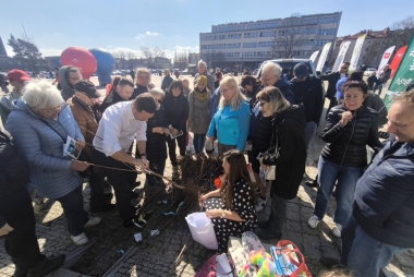 Grupa osób przy sadzonkach drzewek owocowych 