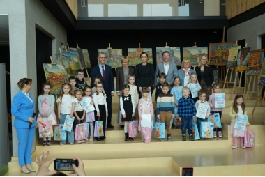 Zdjęcie kilkunastu dzieci trzymających dyplomy i torby z nagrodami oraz kilku dorosłych osób stojących za nimi