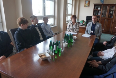 Młodzież siedzi przy stole w gabinecie wicestarosty 