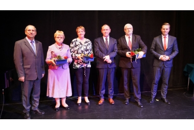 Dwie eleganckie kobiety i czterech mężczyzn w garniturach pozuje do zdjęcia. Uśmiechają się 