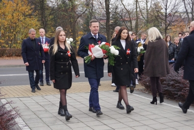 Starosta z kwiatami biało-czerwonymi maszeruje z dwoma uczennicami pod pomnik Piłsudskiego 