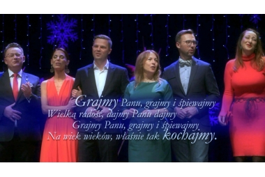Siedmioosobowa grupa elegancko ubranych osób śpiewa "Grajmy Panu" 