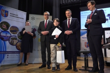 Kobieta i trzech mężczyzn z dzieckiem trzymającym dyplom i statuetkę