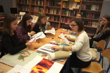 Młodzież pracuje w bibliotece z opiekunem 