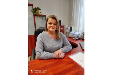 na zdjeciu blondynka w szarej bluzce siedząca z biurkiem - nowa Pani Dyrektor POWDiR