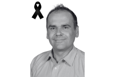 Czarno-białe zdjęcie mężczyzny. W lewym górnym rogu czarna wstęga.