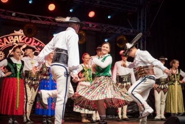 zdjecie przedstawiajace młodzież w strojach góralskich  wykonujących taniec na scenie 
