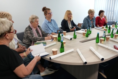 Seniorzy siedza przy stole i rozmawiają
