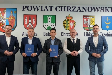 Starosta chrzanowski wraz z przedstawicielami PZD i samorządowcami stoją przed tablicą Powiat Chrzanowski