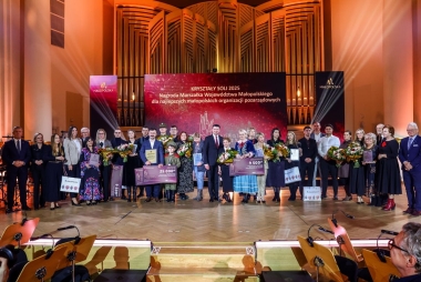 Zdjęcie kilkudziesięciu osób na scenie. Część z nich trzyma kwity, dyplomy i inne podarunki.