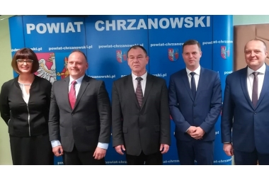 od lewej Ewa Jędrysik, w czarnej garsonce i białej b,luzce, Przemysław Rejdych, Andrzej Uryga, Bartłomiej Gębala, Adam Potocki w ciemnych garniturach, w tle niebiseka scianka z herbami powiatu chrzanowskiego 