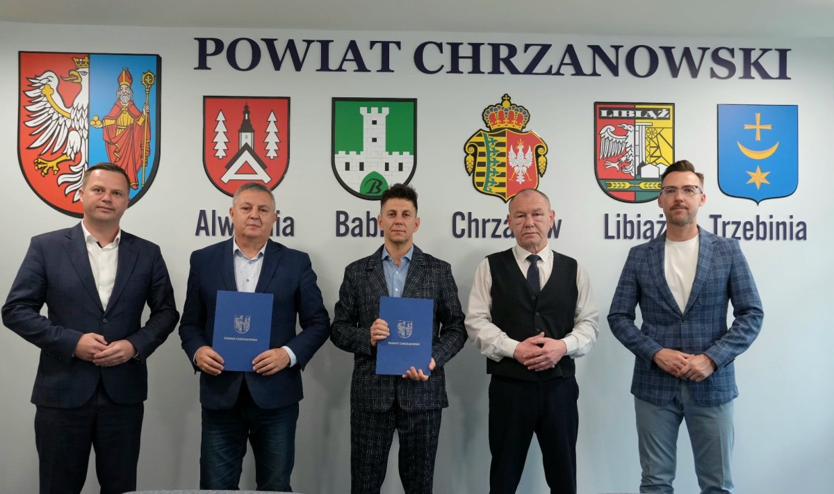 Starosta chrzanowski wraz z przedstawicielami PZD i samorządowcami stoją przed tablicą Powiat Chrzanowski