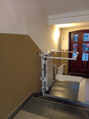 platforma DELTA kolor biało - srebrny przyschodowa do transportu osób niepełnosprawnych - wiidok z góry schodów, w tle drzwi wejściowe 